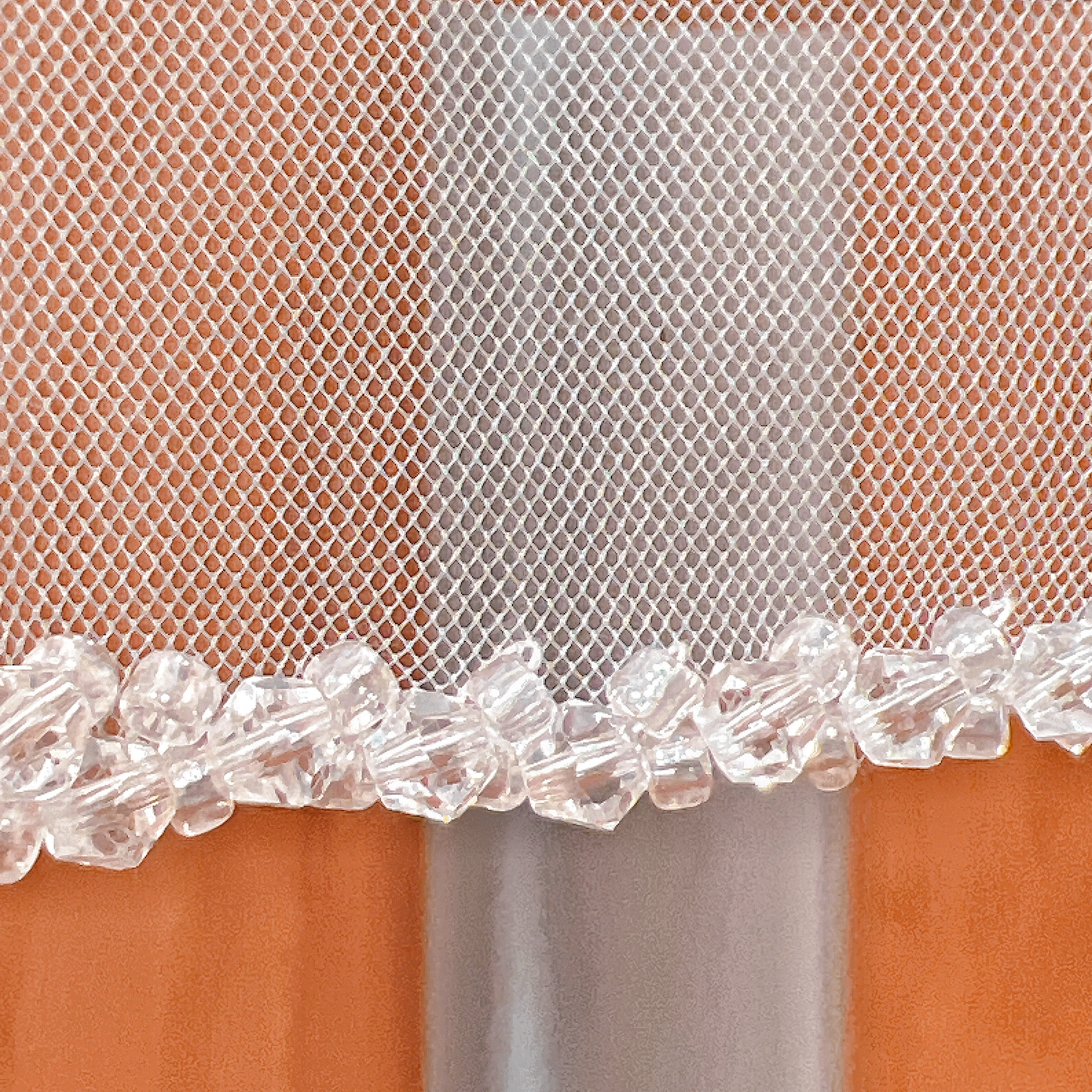 Detailed view of a crystal beaded wedding veil in fingertip length.
