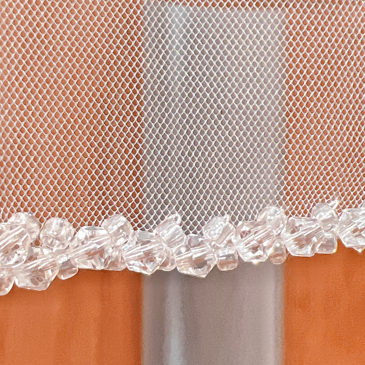 Detailed view of a crystal beaded wedding veil in fingertip length.