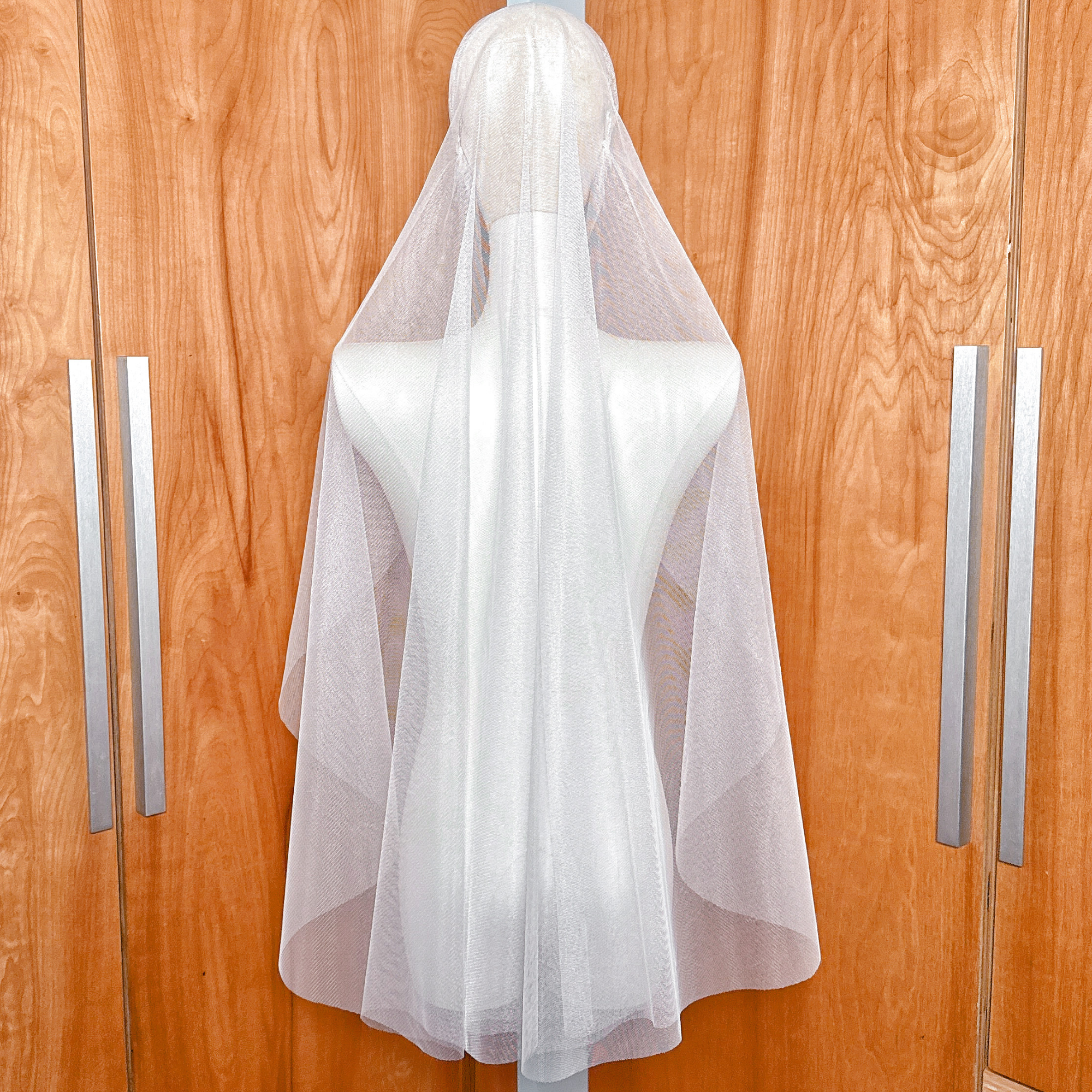 Back view of a fingertip length Juliet cap bridal veil showing the soft drape and raw cut edge on a mannequin.
