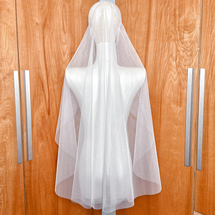 Back view of a fingertip length Juliet cap bridal veil showing the soft drape and raw cut edge on a mannequin.