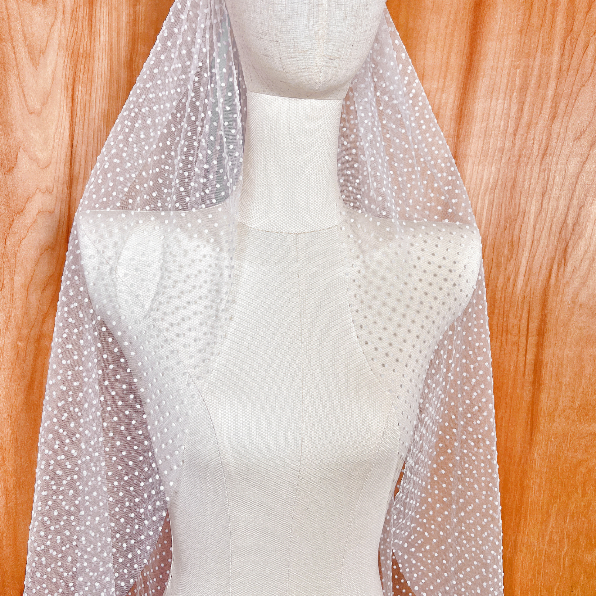 A single-tier polka dot wedding veil shown in a 36-inch fingertip length, displaying a soft, natural drape.