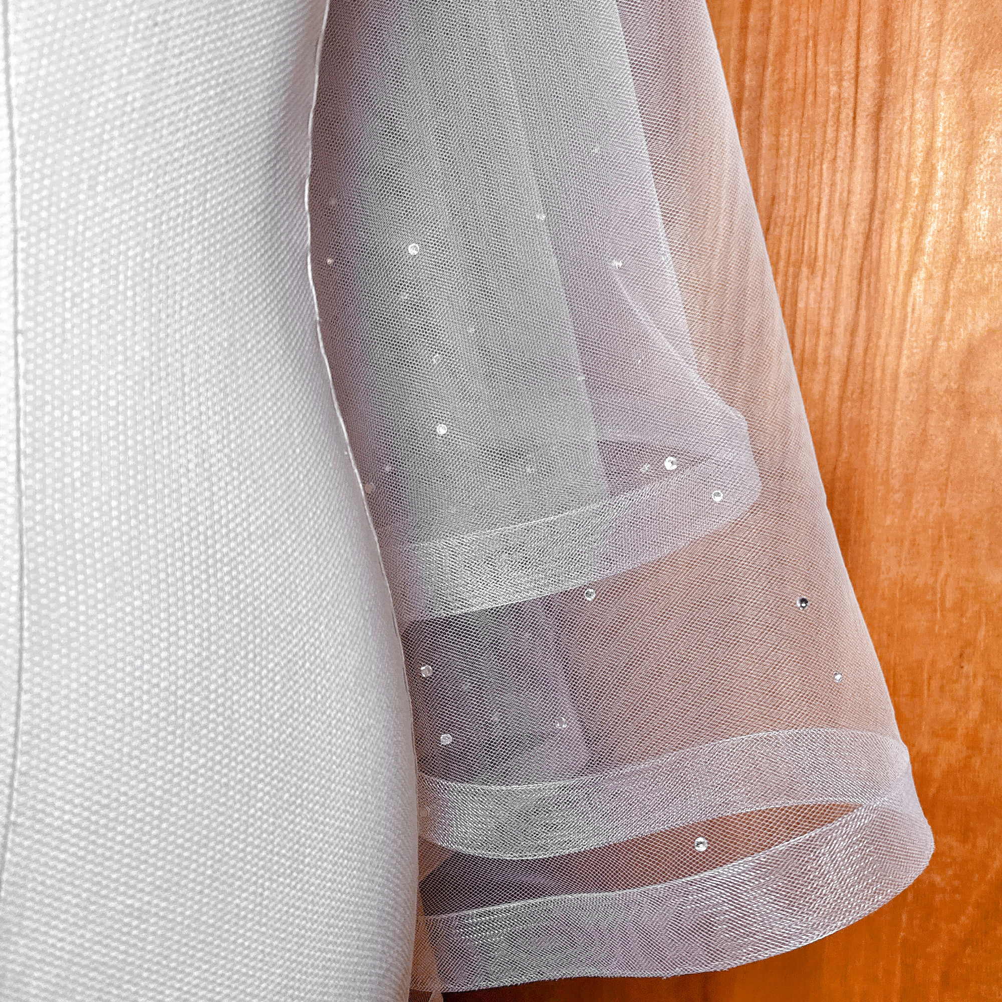 Close-up of the scattered rhinestones on a two tier horsehair wedding veil shown on a mannequin.