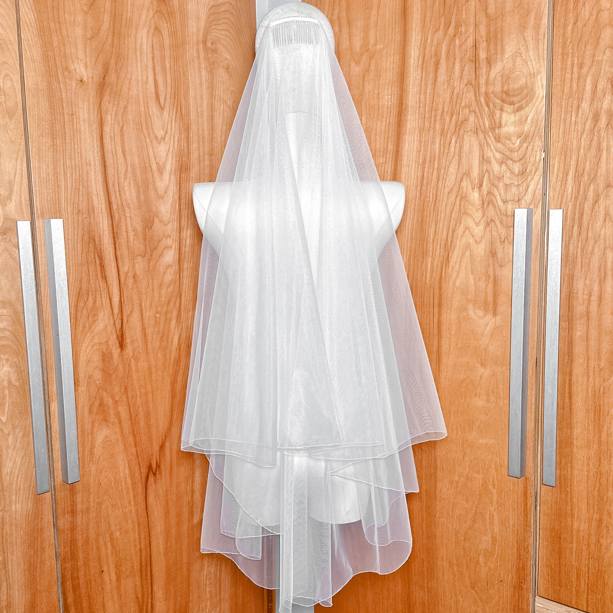 Back view of a Pencil Edge Two Tier Fingertip Length Veil showcasing the cascading tulle layers.