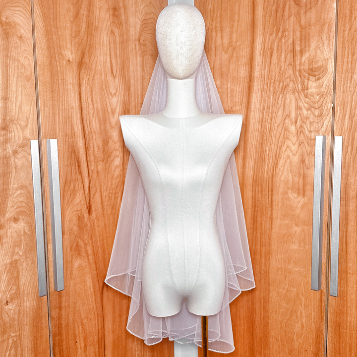 Elegant two tier wedding veil with rhinestone edge shown in fingertip length against a neutral background.