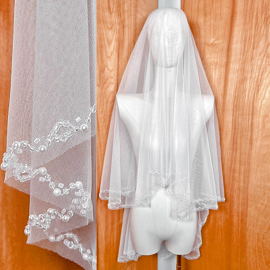 Front view of a fingertip-length two-tier wedding veil featuring a shimmering beaded border.