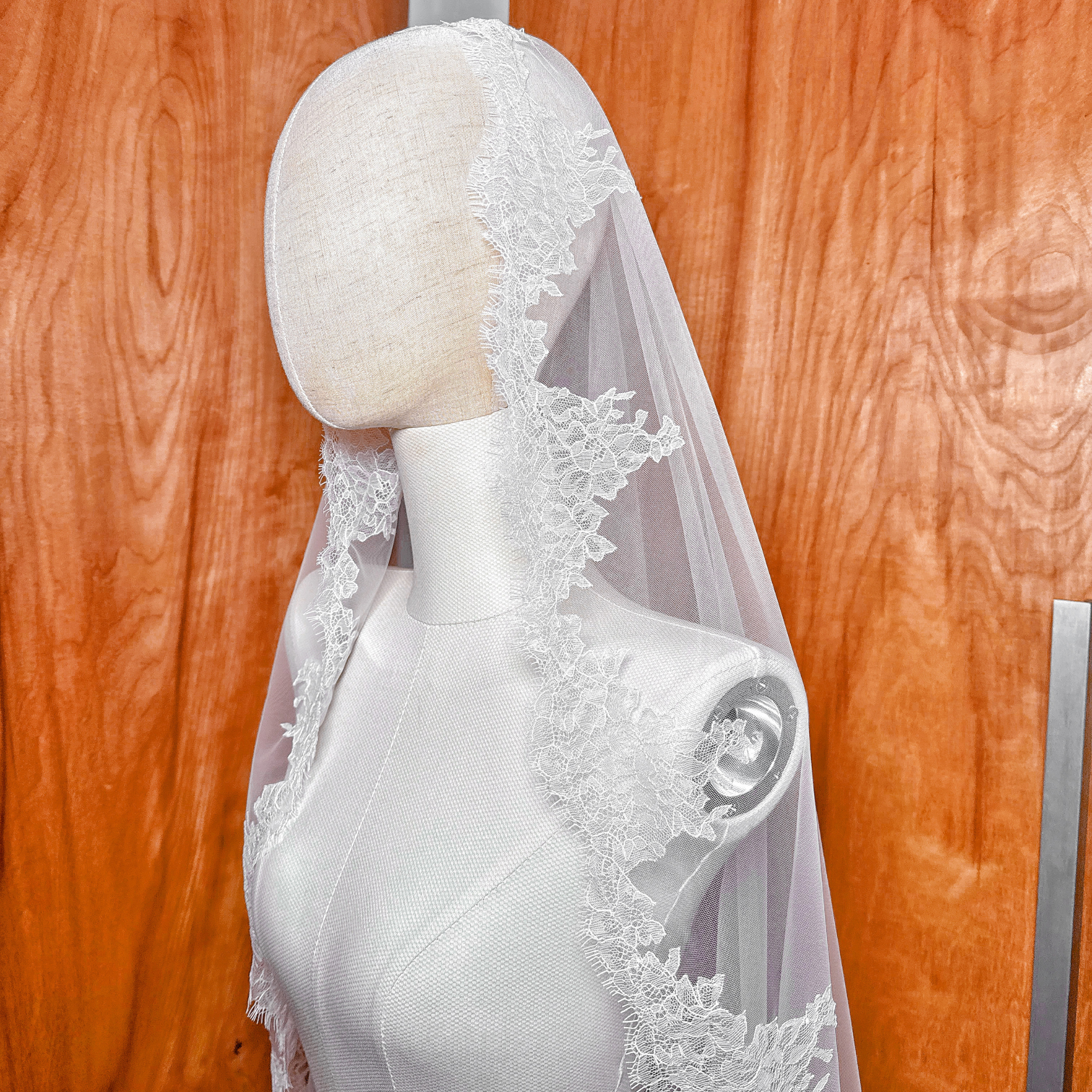 Spanish style mantilla wedding veil in fingertip length featuring delicate Chantilly lace trim on a mannequin.