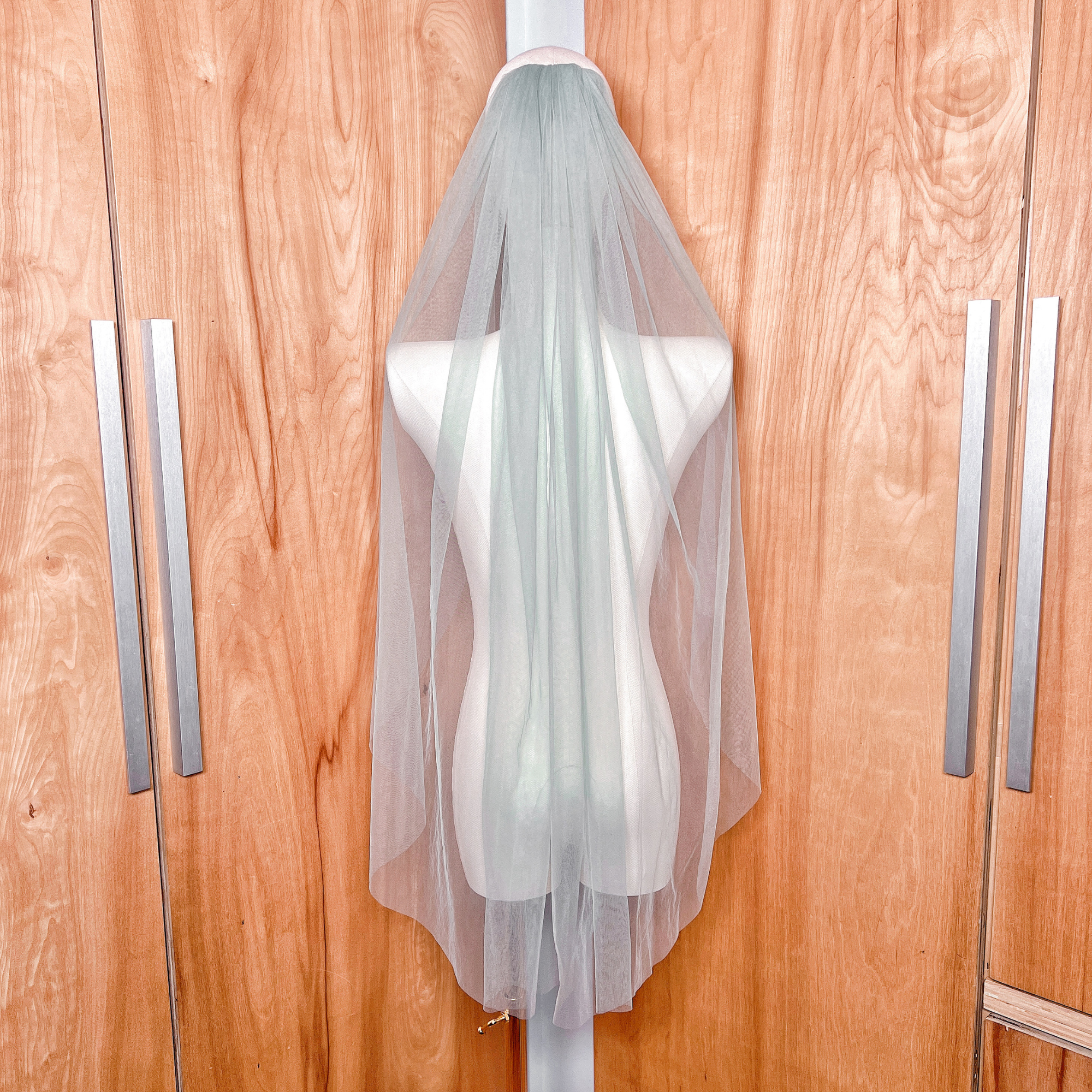 Rear view of a lightweight sage green wedding veil falling to fingertip length.