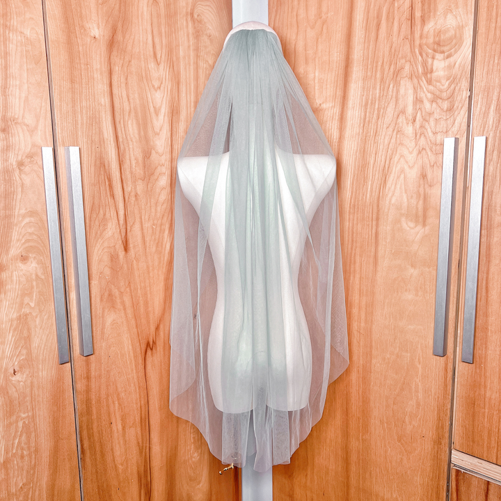 Rear view of a lightweight sage green wedding veil falling to fingertip length.