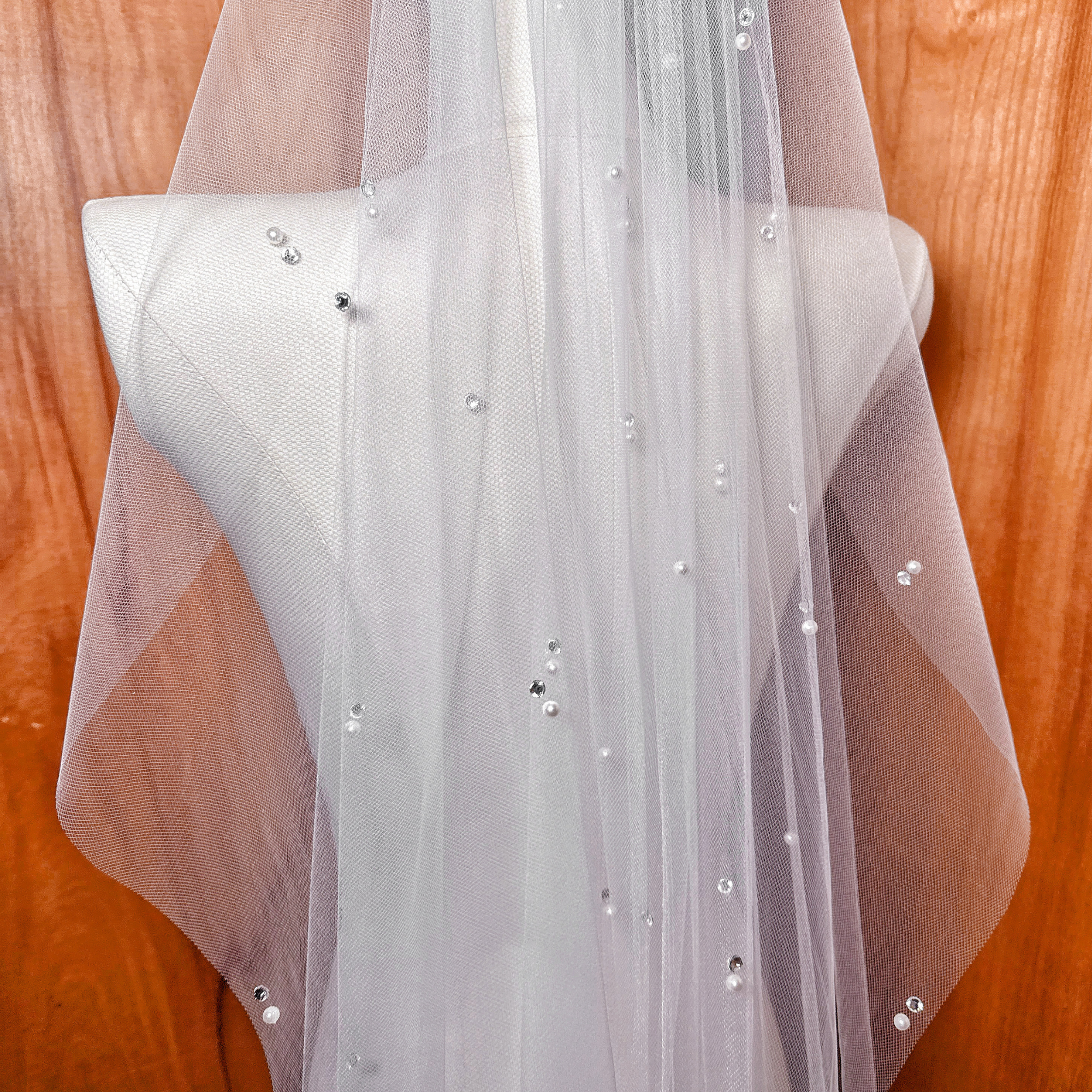 High-resolution shot highlighting the sheer tulle texture and rhinestone accents of the scattered pearl wedding veil.