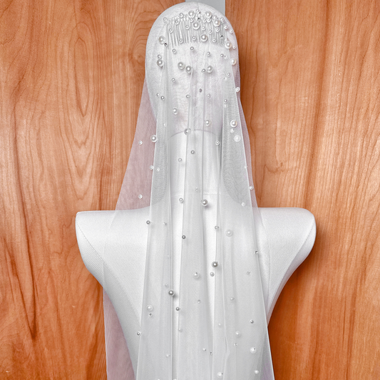 Close up detail of the intricate scattered rhinestone and pearl embellishments on a sheer fingertip length wedding veil.