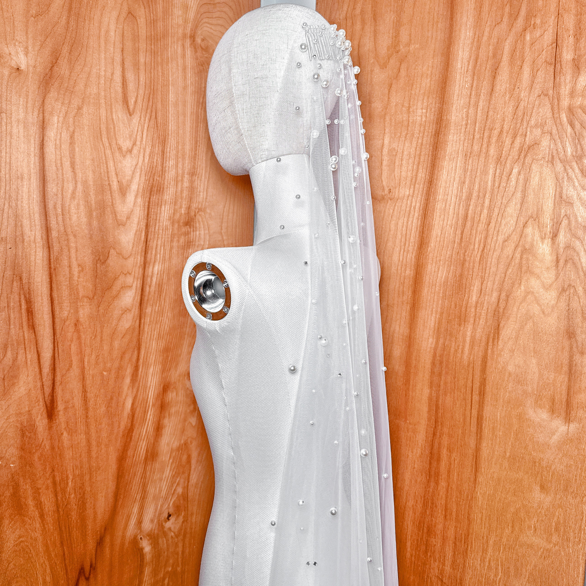 Side profile of a fingertip length scattered rhinestone and pearl wedding veil showing how the fabric falls at the waist.