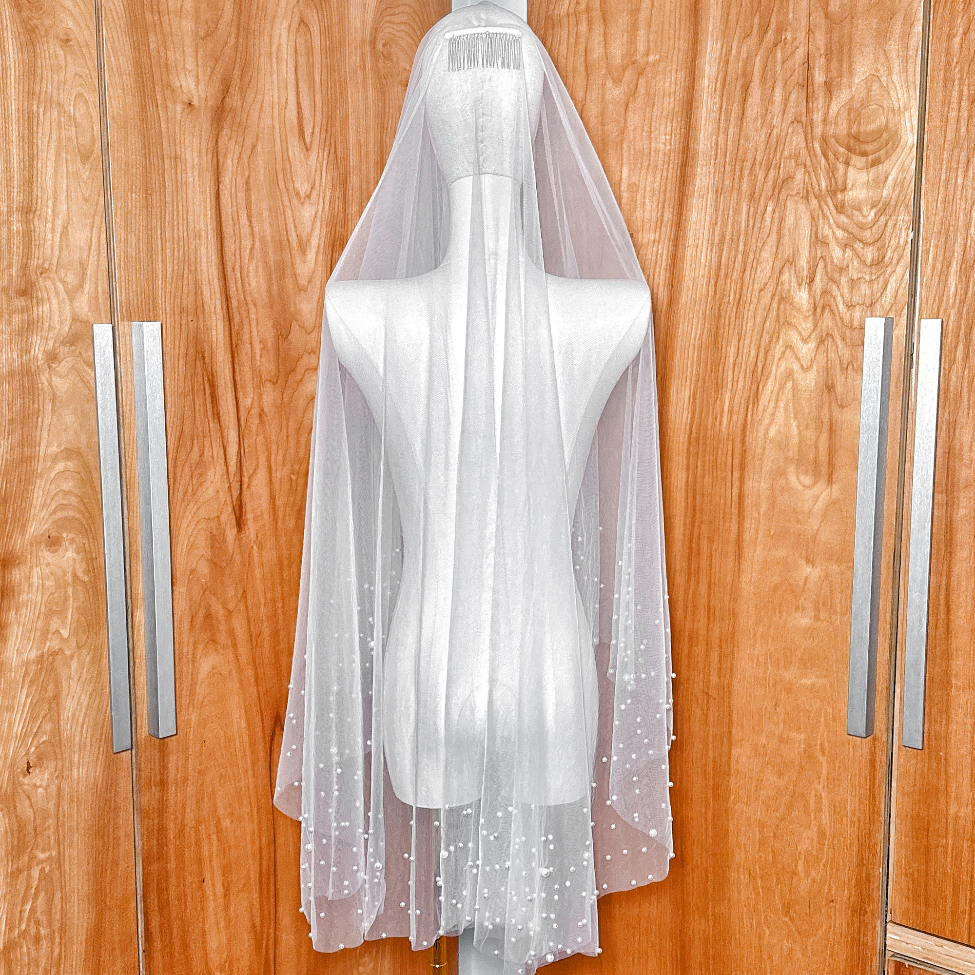 Back view of a fingertip length two tier scattered pearl wedding veil showing the layered tulle effect.