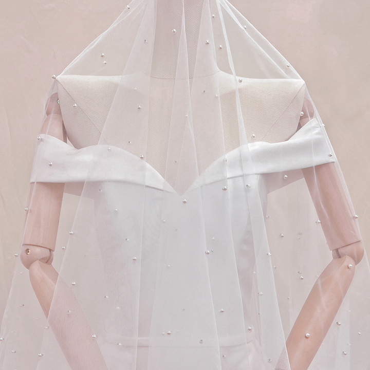 Detailed close-up of the scattered pearls on a two-tier fingertip length wedding veil with blusher.