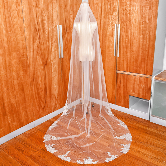 Full-length back view of a cathedral floral applique wedding veil draped over a mannequin.