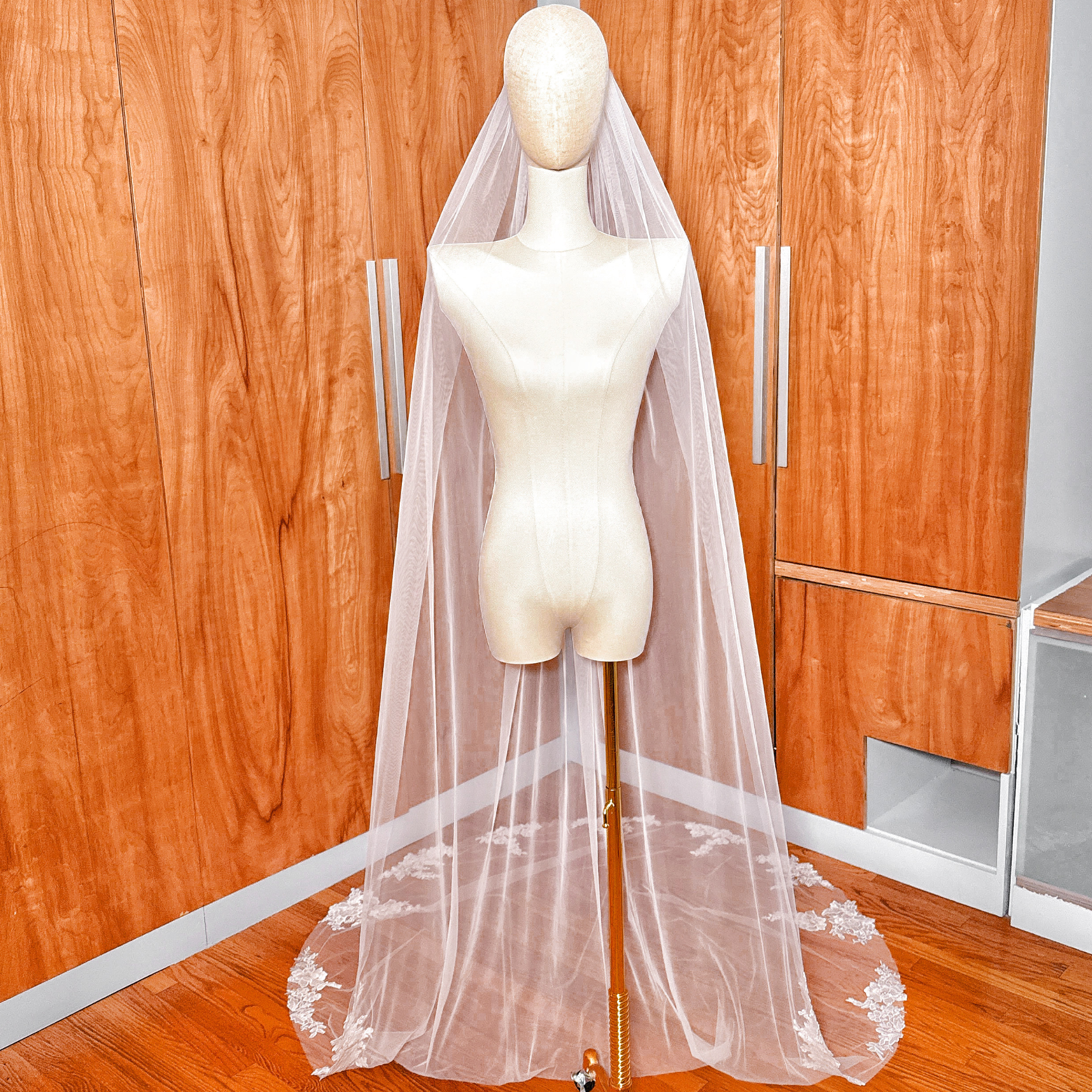 A long cathedral length floral applique wedding veil displayed on a mannequin.