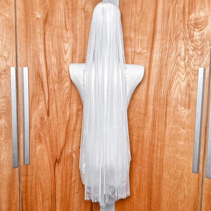 Back view of the sheer fingertip length floral beaded edge wedding veil cascading elegantly.
