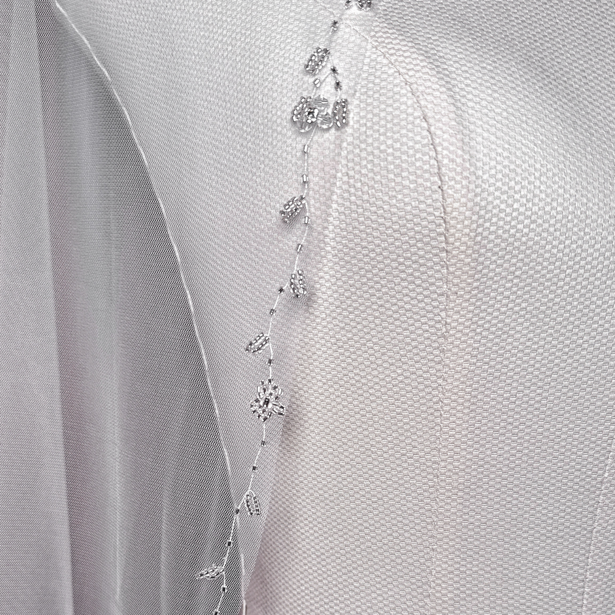 Close-up of the delicate floral beadwork and crystals along the edge of the fingertip wedding veil.
