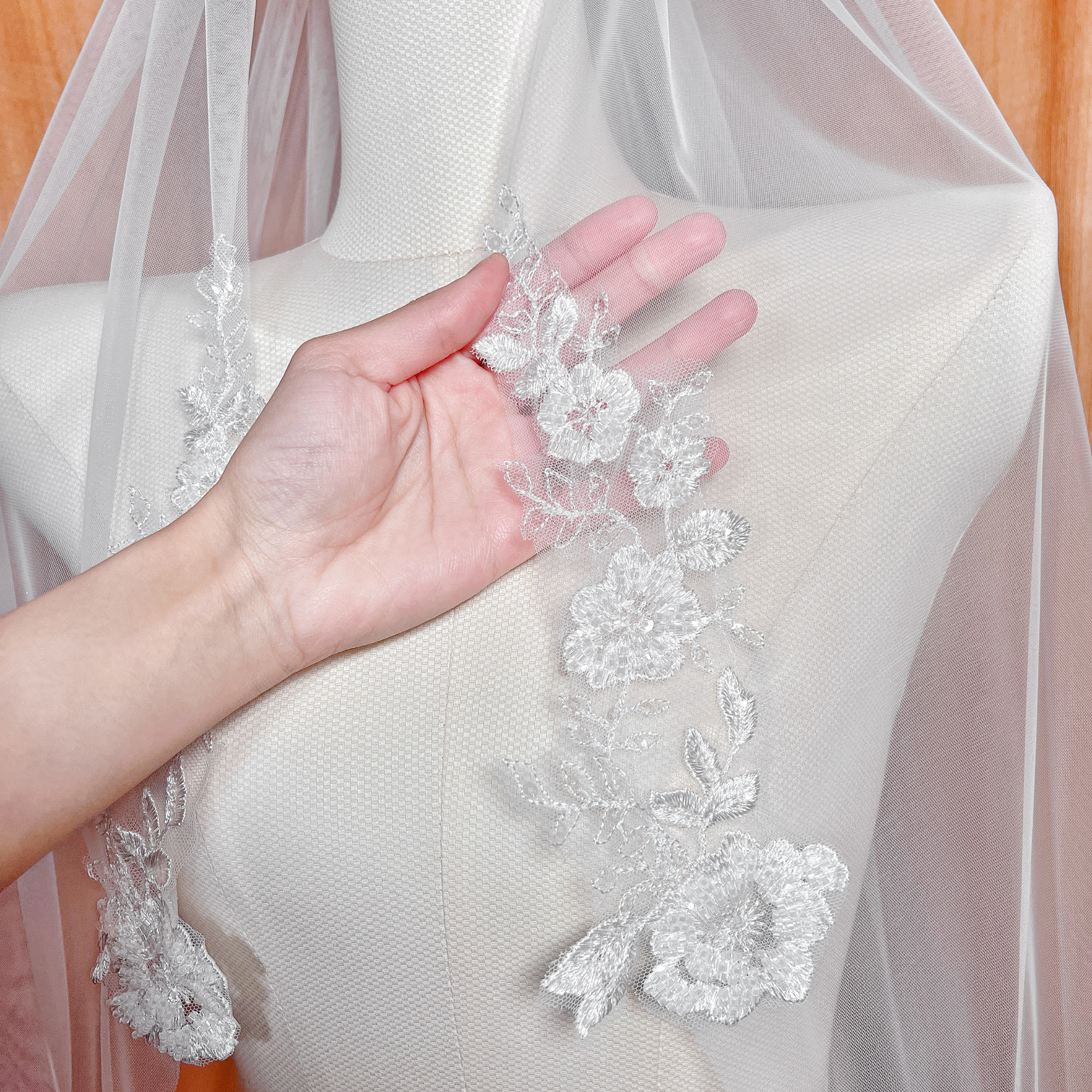 Close up of the intricate floral beaded lace details on a fingertip length wedding veil.