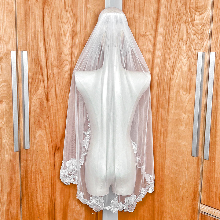 Side view of a floral lace edge wedding veil in fingertip length shown on a professional mannequin.