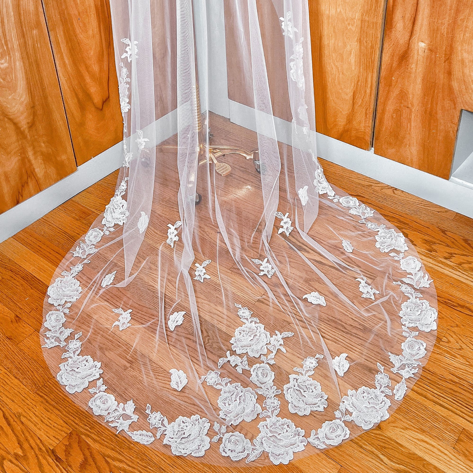 Close-up of the intricate floral lace edge on a long train wedding veil shown on a mannequin.