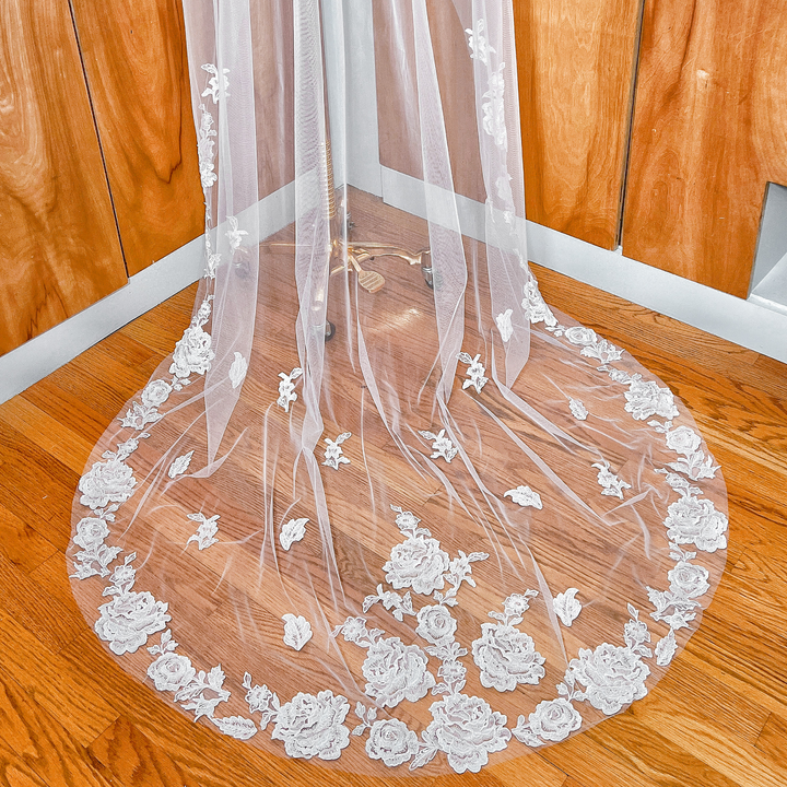 Close-up of the intricate floral lace edge on a long train wedding veil shown on a mannequin.