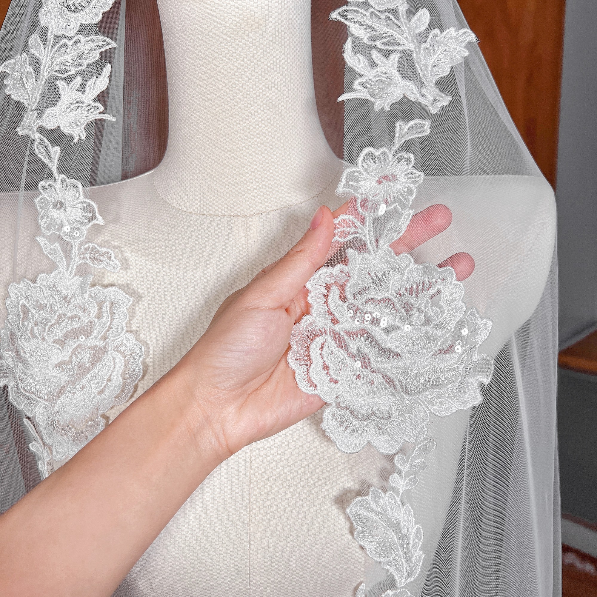 Close-up of the intricate floral lace edging on a royal cathedral length mantilla wedding veil shown on a mannequin.