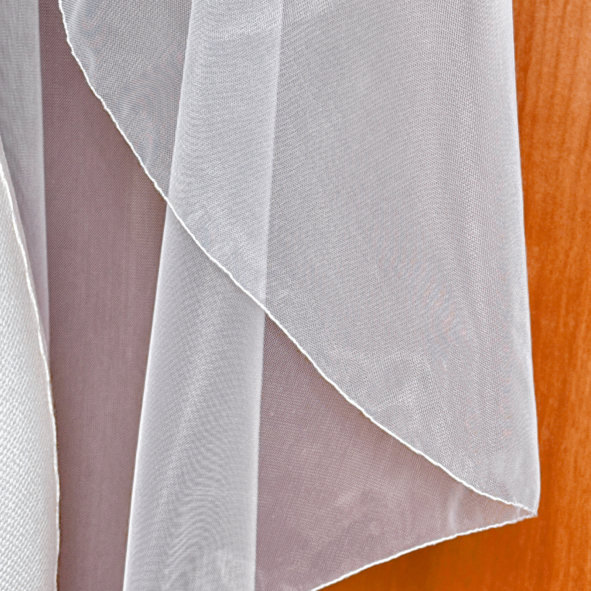 Layered folds of a cascade fingertip length wedding veil.