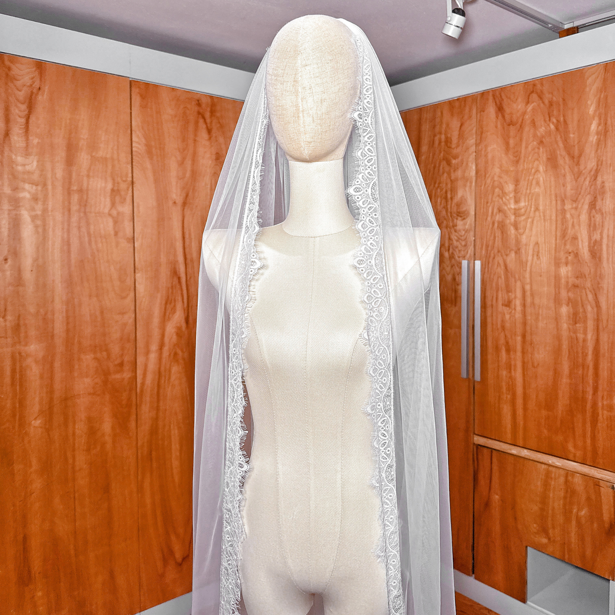 French-style Chantilly lace veil in cathedral length draped over a white mannequin.