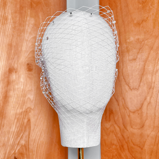 Front view of a bridal bandeau birdcage wedding veil embellished with shiny rhinestones.