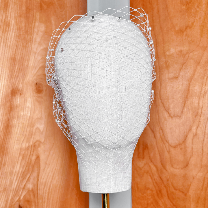 Front view of a bridal bandeau birdcage wedding veil embellished with shiny rhinestones.