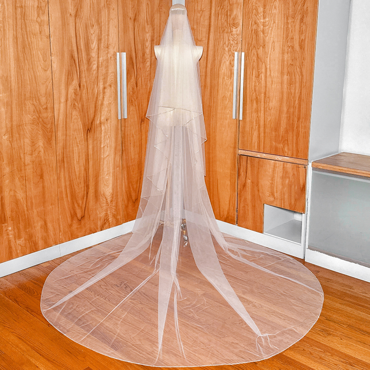 Complete wide back view displaying the full drama and wide train of a two-tier cathedral length wedding veil with a sparkling rhinestone edge.