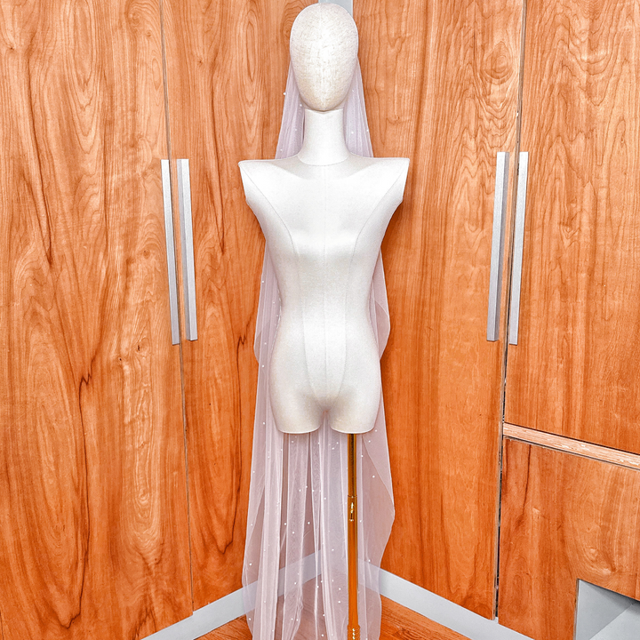 Full-length view showing the elegant drape and cascading pearl placement of the bridal veil.