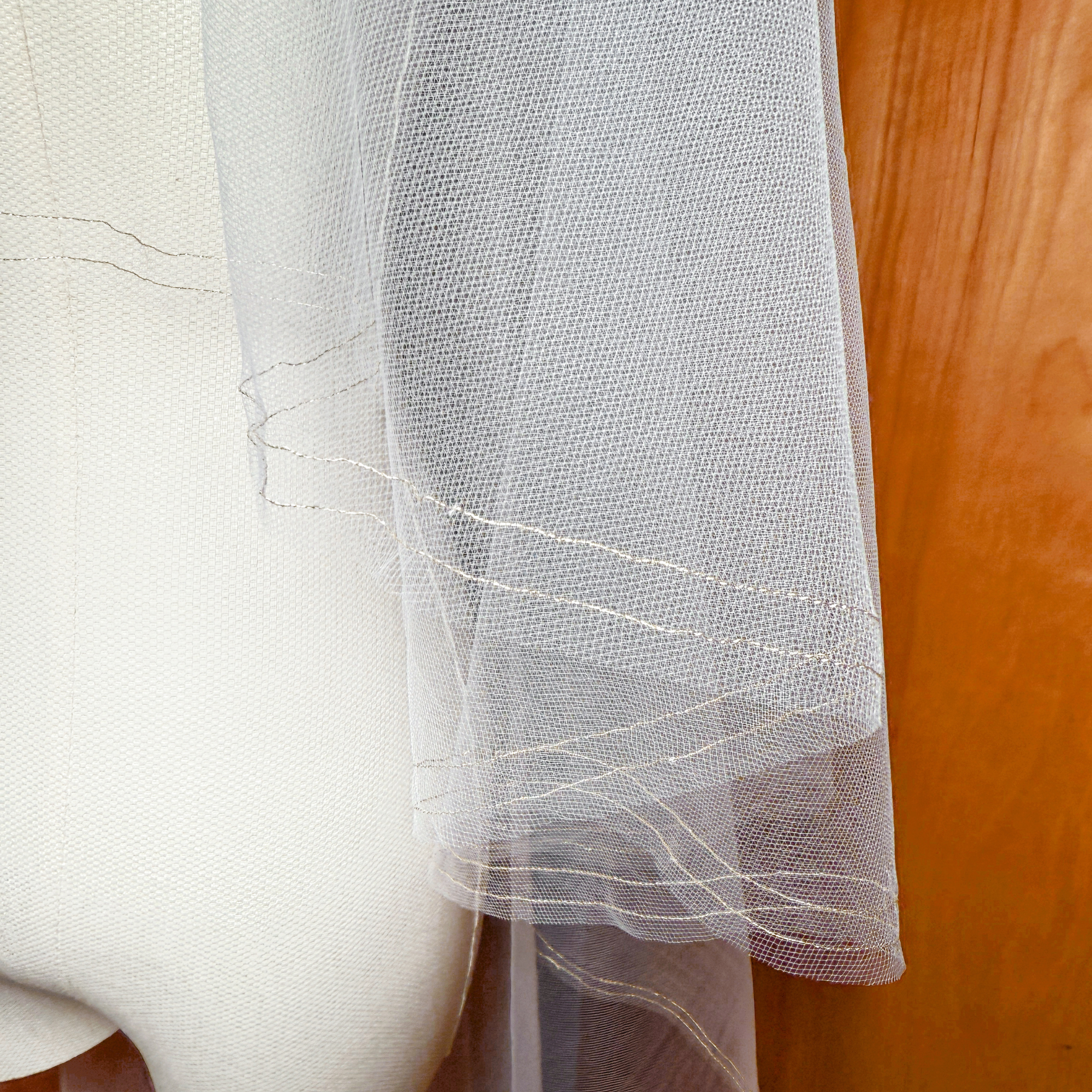 Close-up of a two tier veil featuring a gold metallic trim and blusher, displayed on a bridal mannequin in waltz length.
