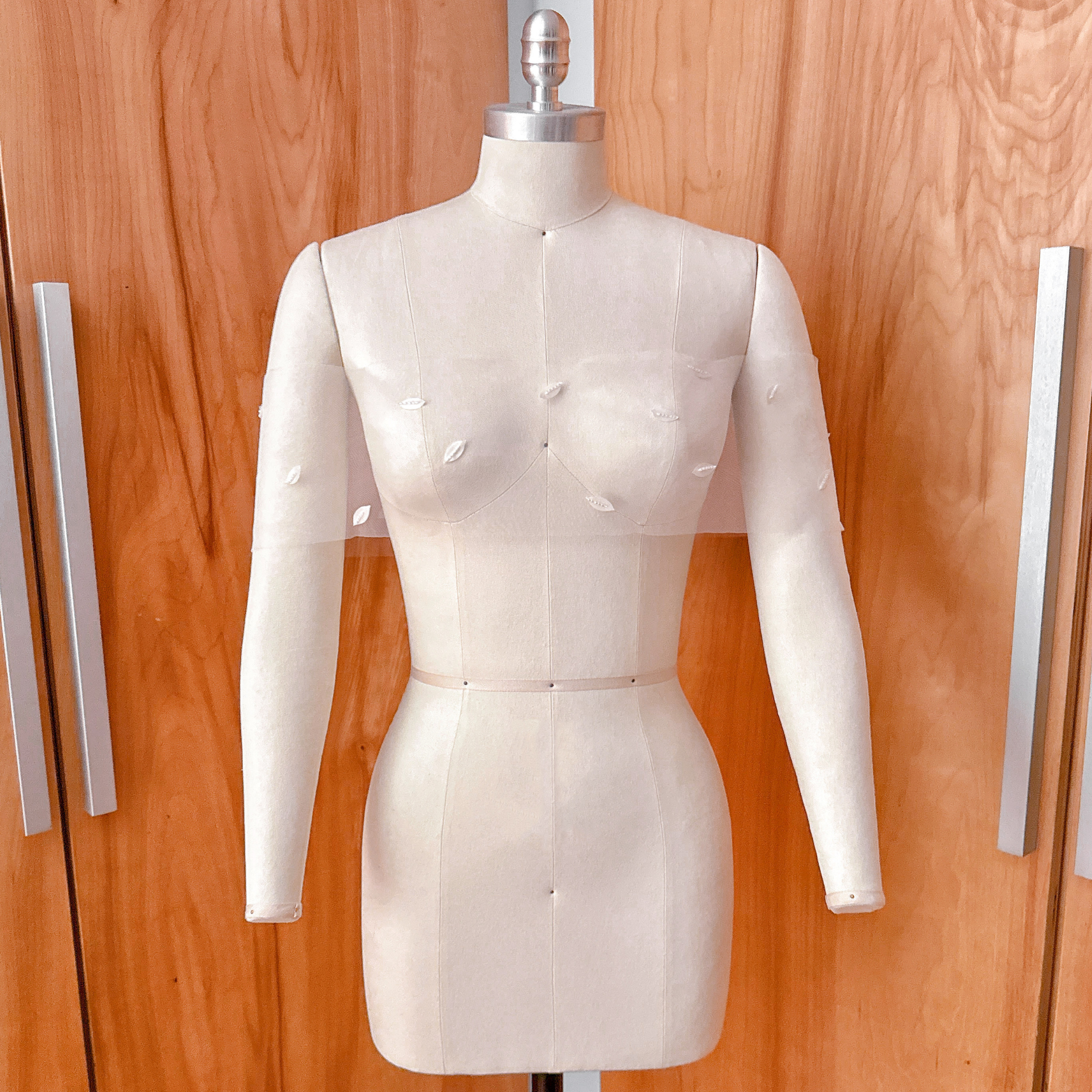 A side-angle studio shot of the 3D petal illusion bridal wrap on a dress form, showcasing the organic scatter and drape across the shoulders.
