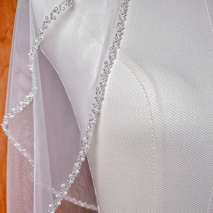 Close-up view of the intricate beadwork on a hip length beaded edge two tier wedding veil.