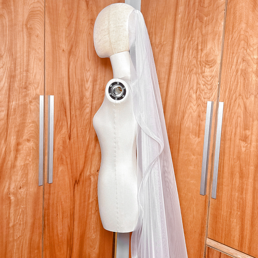 Side profile of a cascading cathedral length bridal veil with 1.5 inch horsehair trim on a mannequin.
