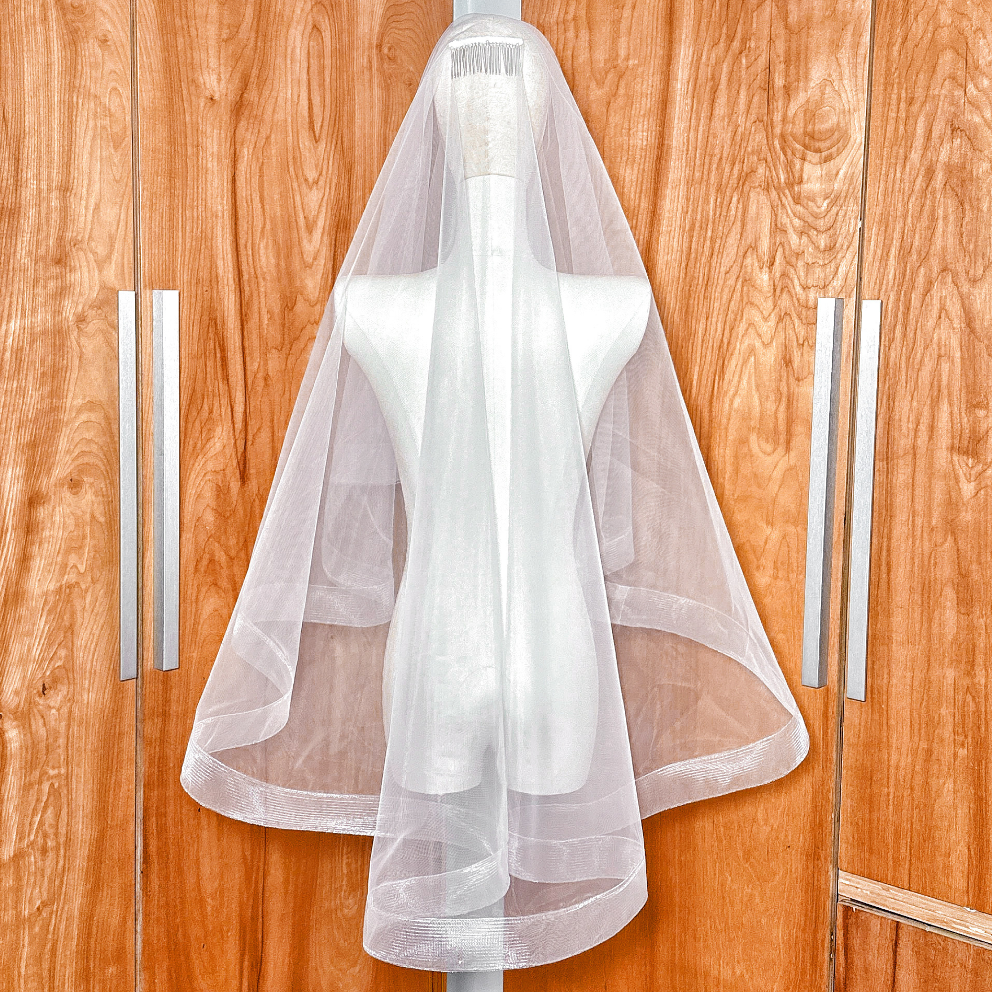 Fingertip length wedding veil featuring a 2 inch horsehair trim and blusher shown on a bridal mannequin.