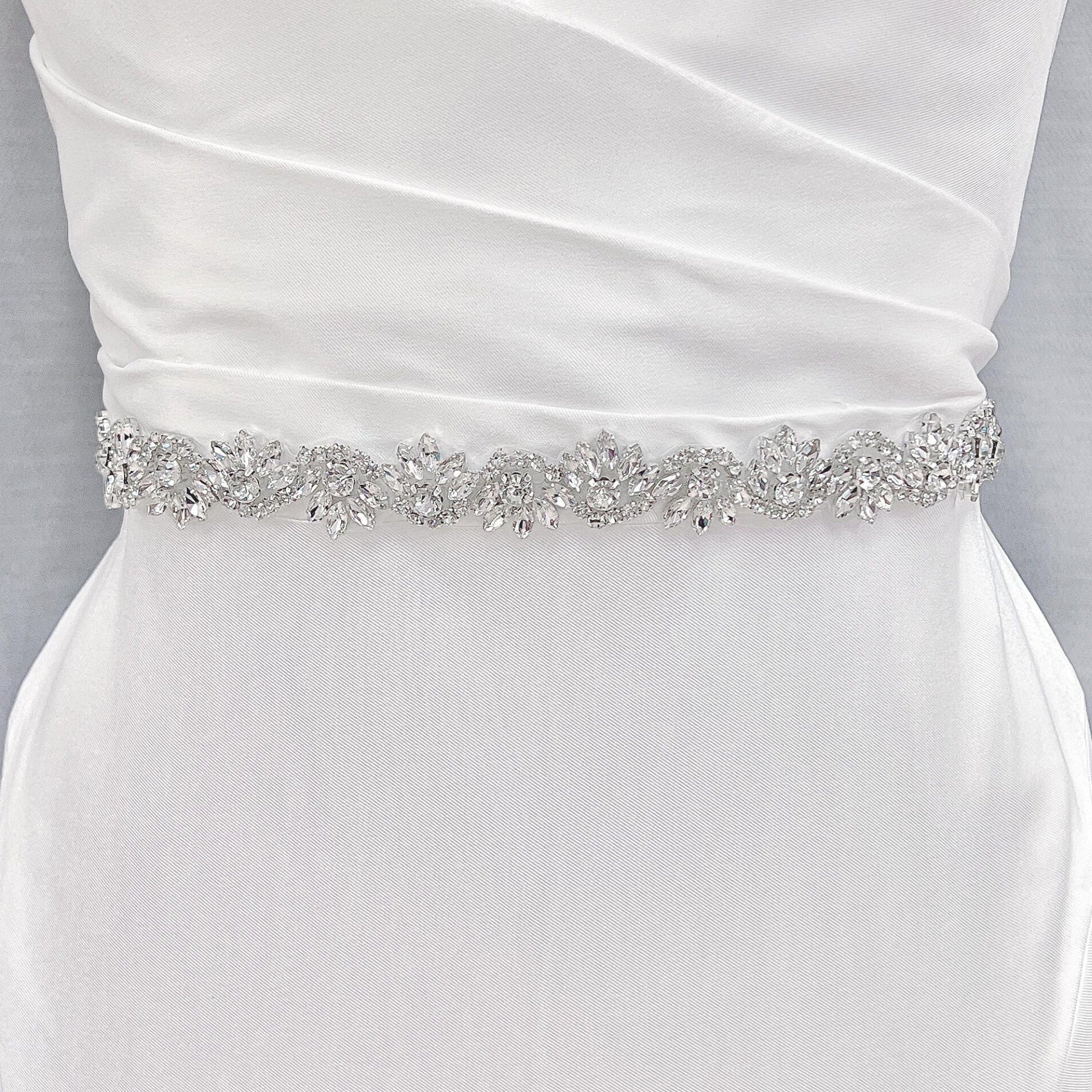 Detailed view of the sparkling embroidery on a silver beaded bridal belt pinned to a bridal mannequin.