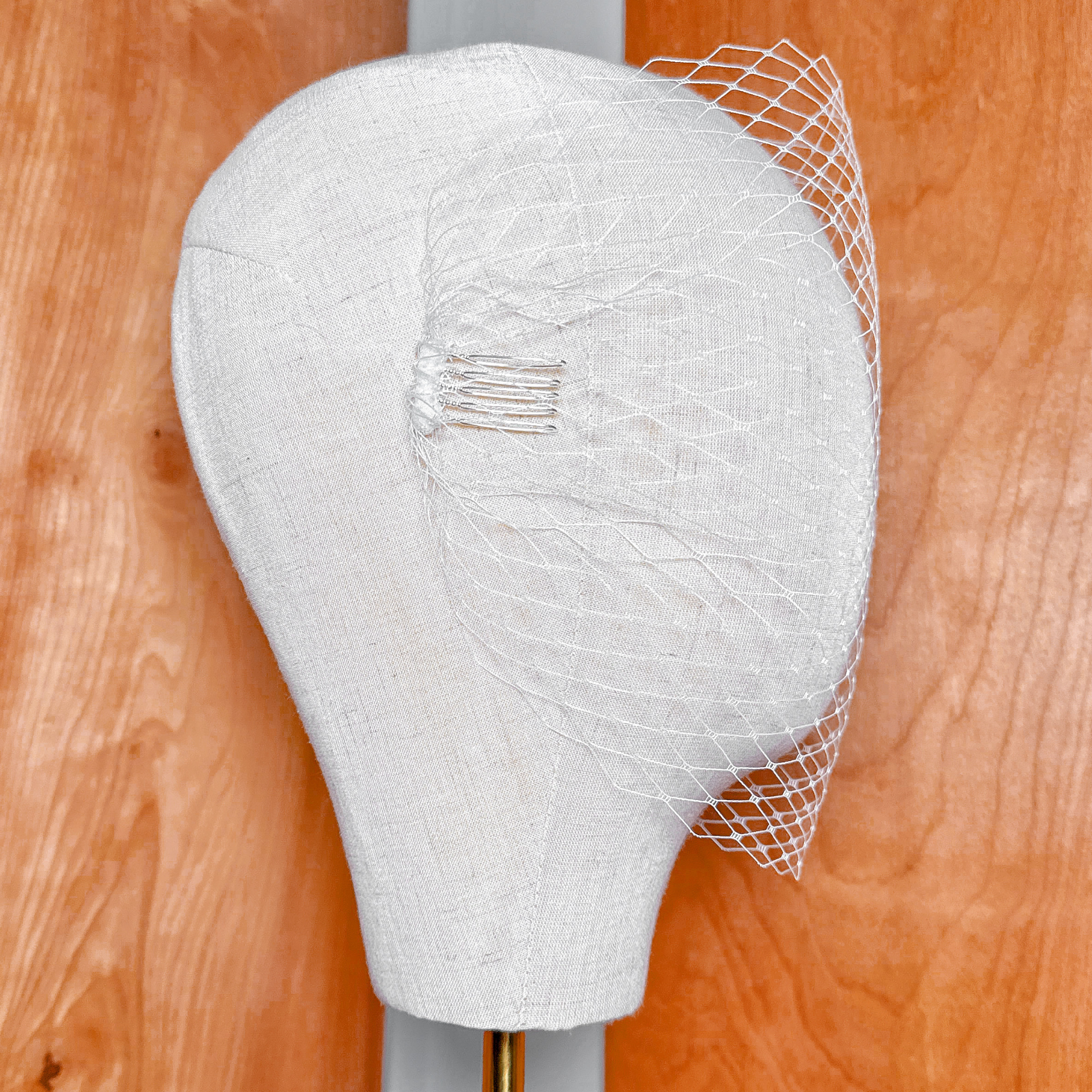 Detailed texture of an ivory bandeau birdcage wedding veil gathered on a display head.
