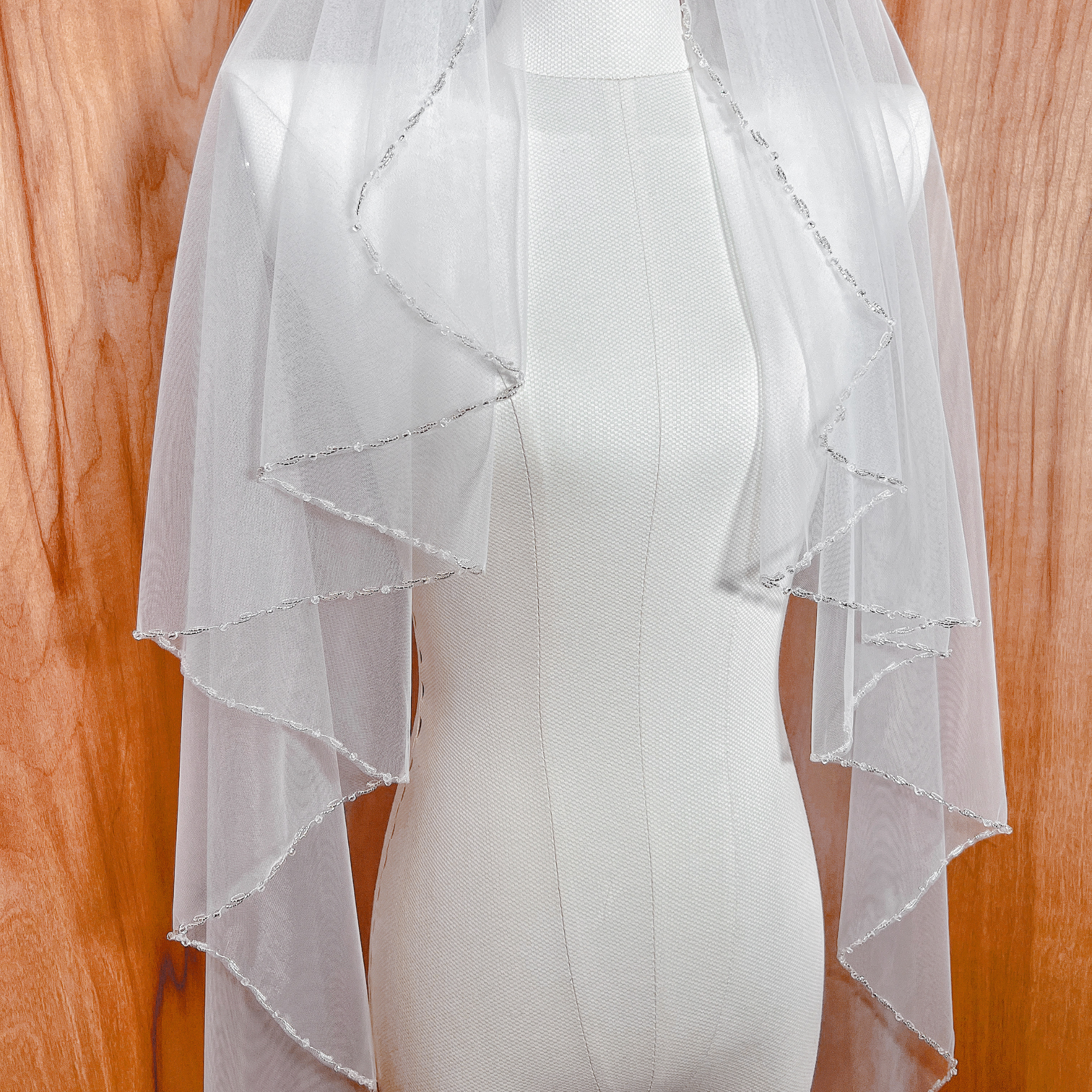  Close up of the intricate beadwork on a ivory beaded edge wedding veil.