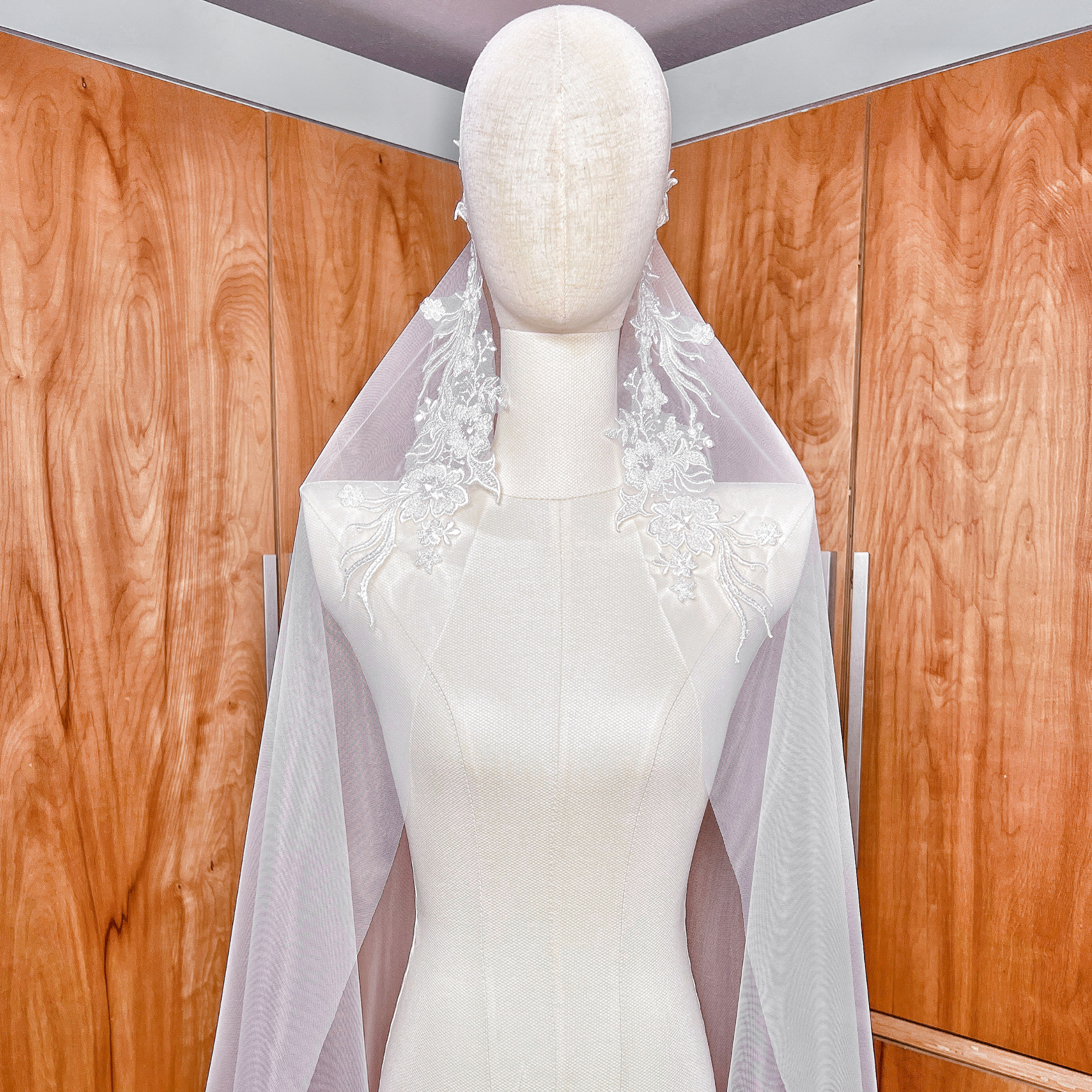 High-resolution detail of the ivory soft bridal tulle and beaded lace trim on a cathedral length mantilla veil displayed on a mannequin.