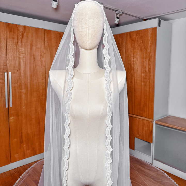 Close-up of the ivory soft English tulle and hand-sewn beadwork of a royal cathedral beaded mantilla wedding veil on a mannequin.
