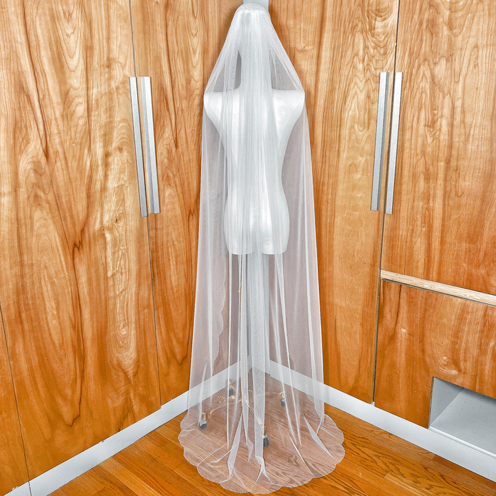 Back view of an ivory wedding veil with a beaded scalloped edge showing its sheer tulle texture and flow.