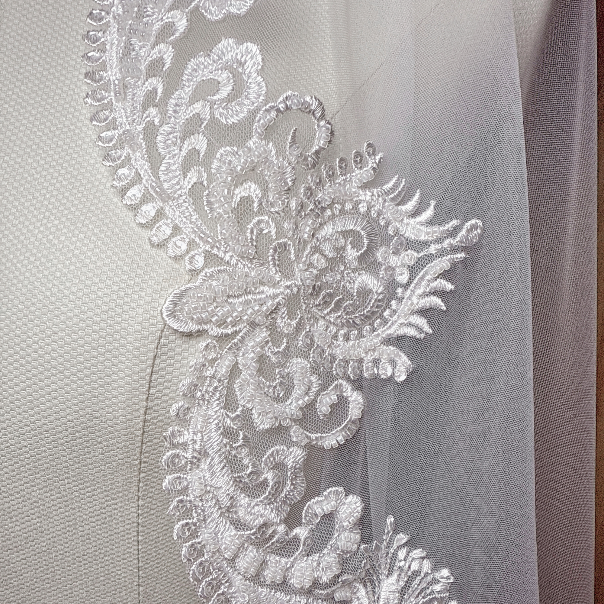Detail view of a Beaded Scalloped Lace Mantilla Veil on a mannequin, highlighting the shimmering beads and classic Spanish-style lace edges.