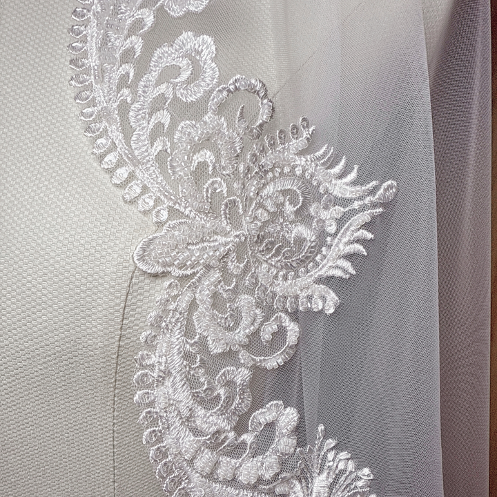 Detail view of a Beaded Scalloped Lace Mantilla Veil on a mannequin, highlighting the shimmering beads and classic Spanish-style lace edges.
