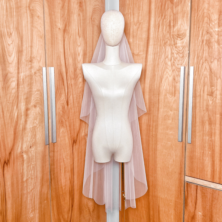 Elegant drape of an ivory cascade knee-length wedding veil with a simple raw edge design.
