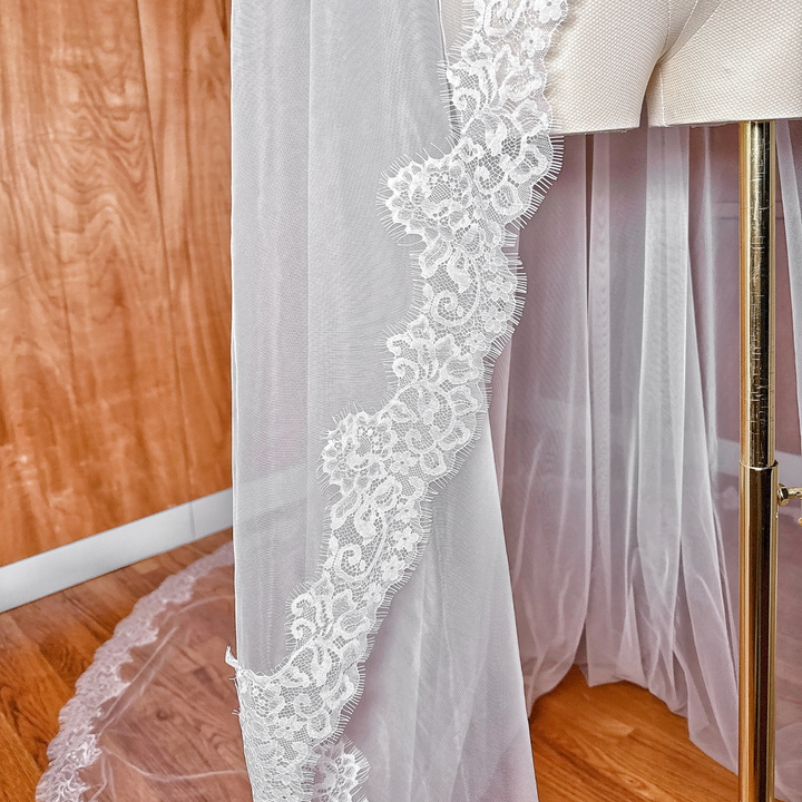 Light ivory Chantilly lace mantilla wedding veil in a cathedral length, showcasing the soft tulle and scalloped lace edges.