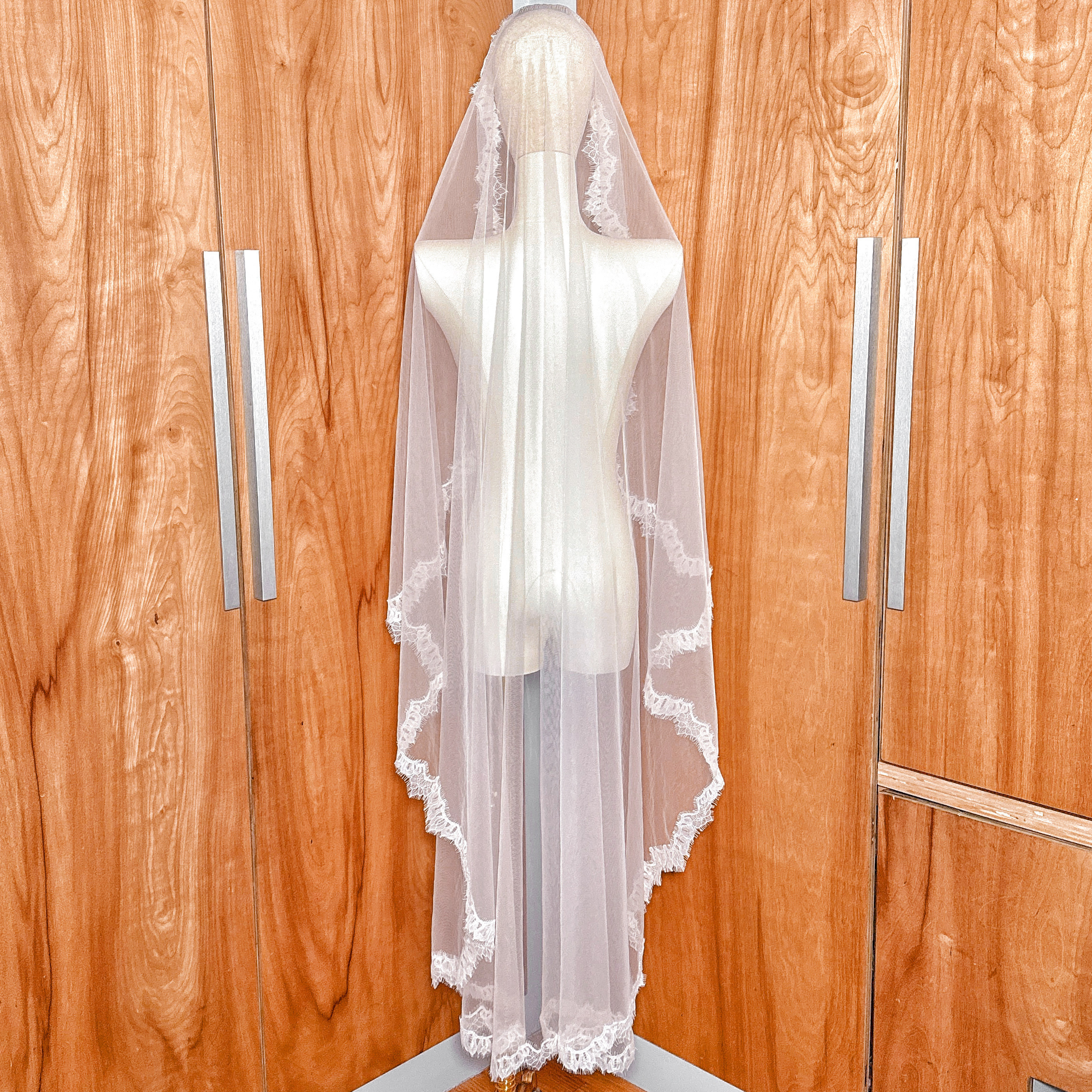 Ivory Chantilly lace mantilla wedding veil in waltz length, showcasing the 60-inch fall from a mannequin's crown.