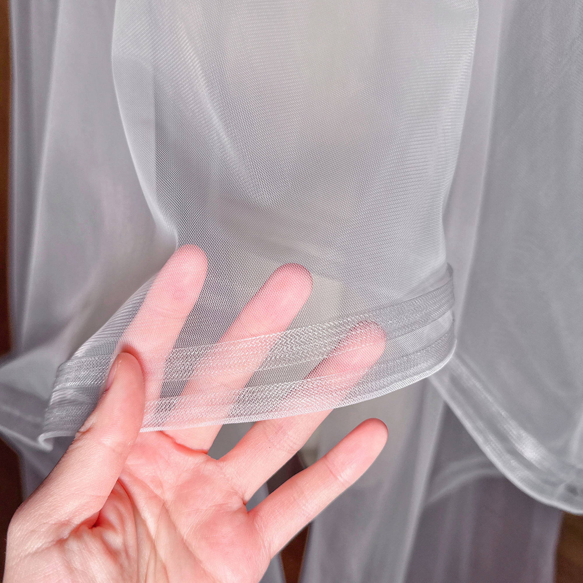 Close-up of the trim on a ivory double horsehair cathedral wedding veil.