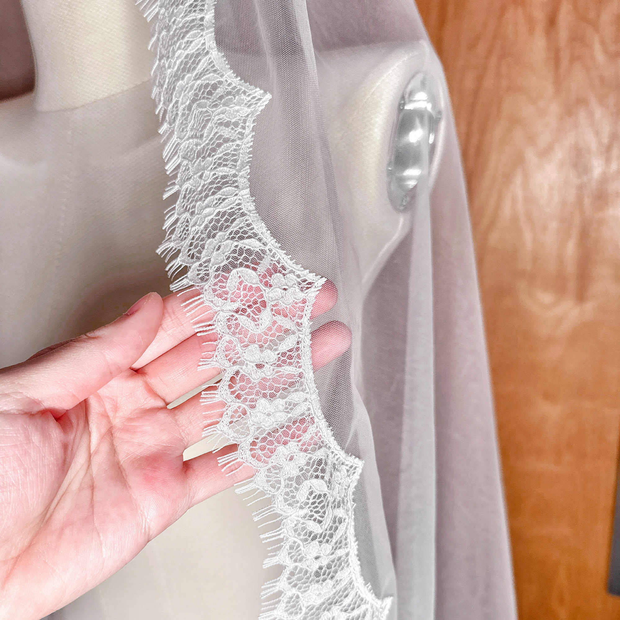Close-up of the delicate eyelash lace trim on a waltz length mantilla bridal veil.